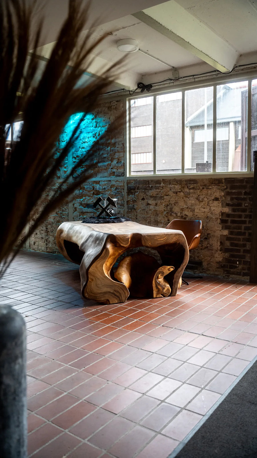 Designertisch mit Baumstamm-Gestell vor Fenstern, hochwertige Einrichtung im Möbelhaus MÖBELLOFT auf Zollverein