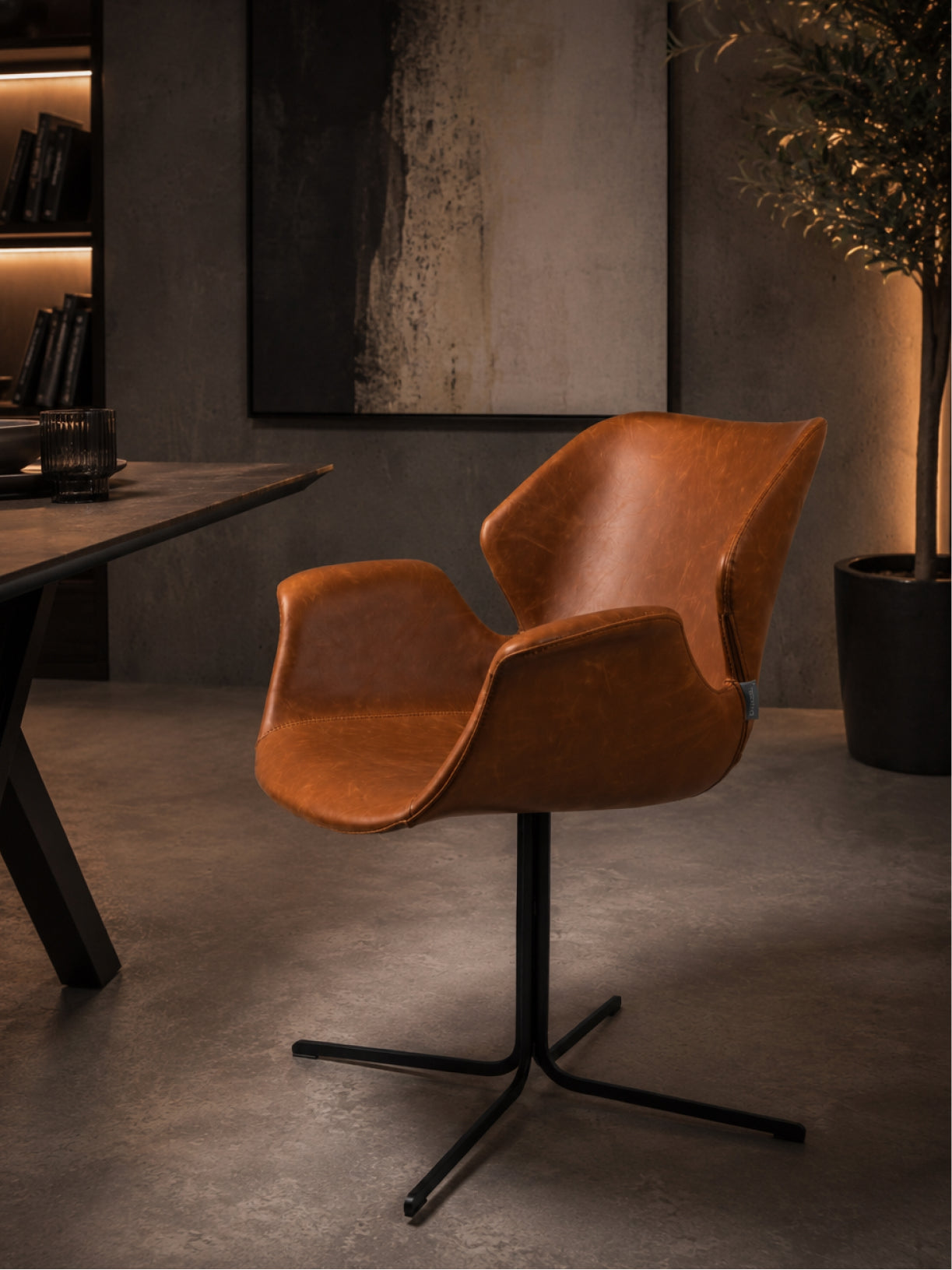 Design Stuhl Falke in Seitenansicht mit ergonomischer Sitzschale, cognacbraunem Leder und schwarzem Fußgestell
