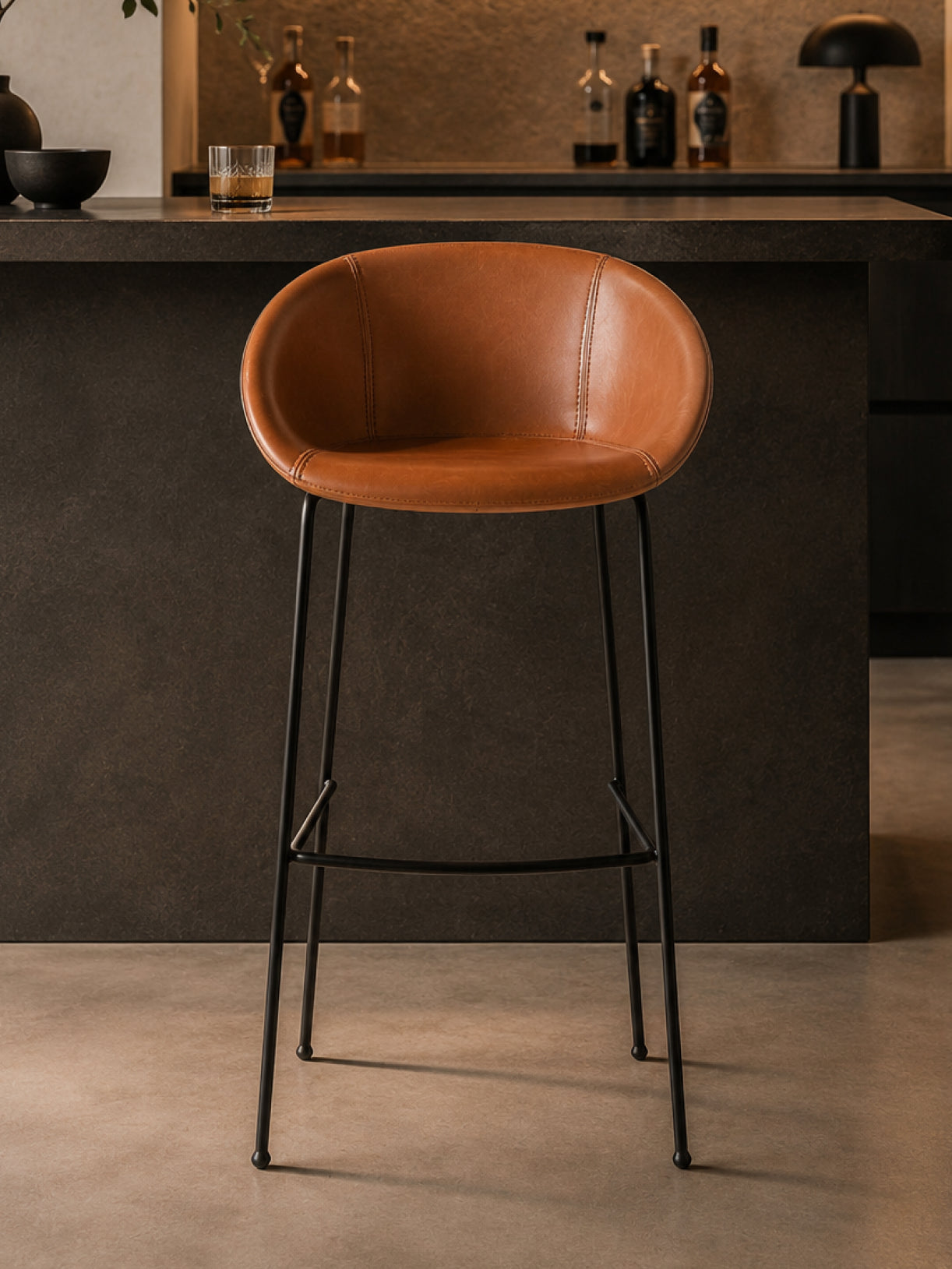 Barhocker Monkey in Frontalansicht mit gepolsterter Sitzschale und schwarzem Stahlgestell vor einer minimalistischen Hausbar