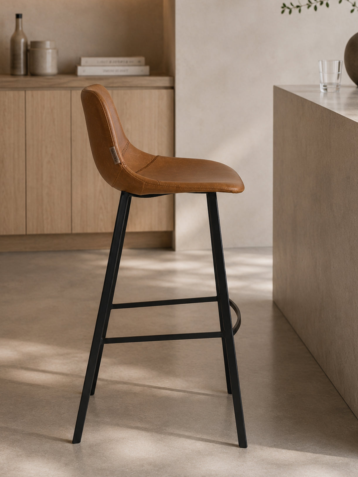 Barhocker Ross in Seitenansicht mit ergonomischer Sitzschale, schwarzem Stahlgestell und heller minimalistischer Hausbar im Hintergrund