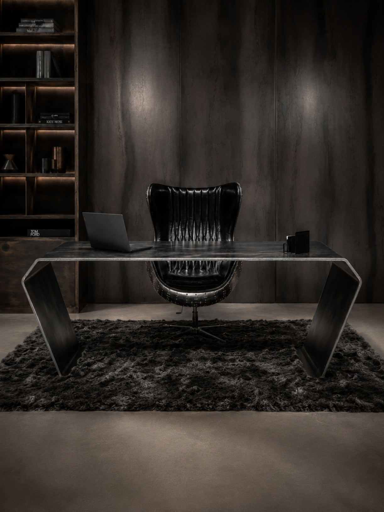 Dunkler Design-Schreibtisch aus Stahl in Frontalansicht mit skulpturalem Untergestell und luxuriösem Office-Ambiente