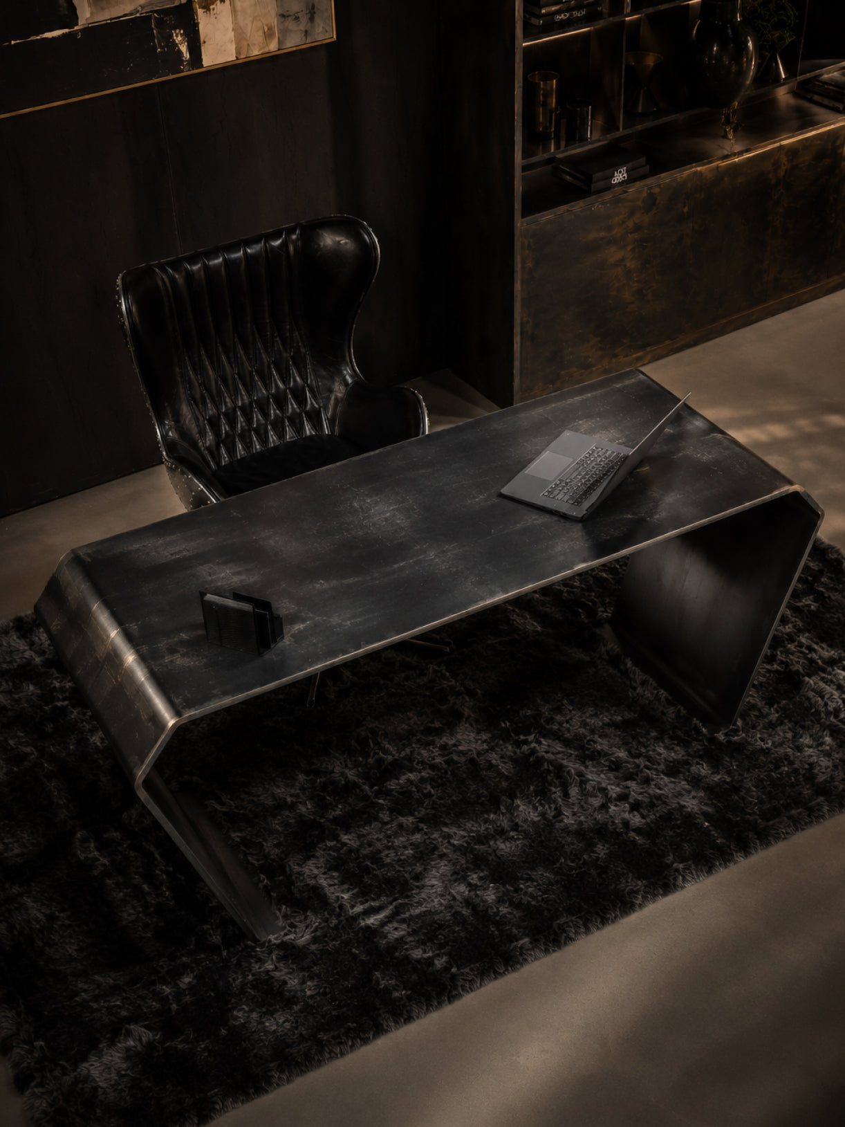 Design-Schreibtisch aus dunklem Stahl in schräger Oberansicht mit markanter Formgebung in einem edlen, dunklen Office-Szenario