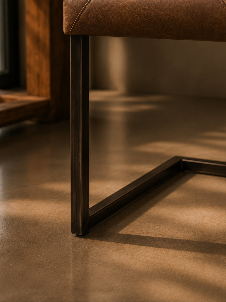 Detailbild vom Stuhl Bega mit dunklem Freischwinger-Gestell und gepolsterter Sitzfläche in brauner Vintage-Optik