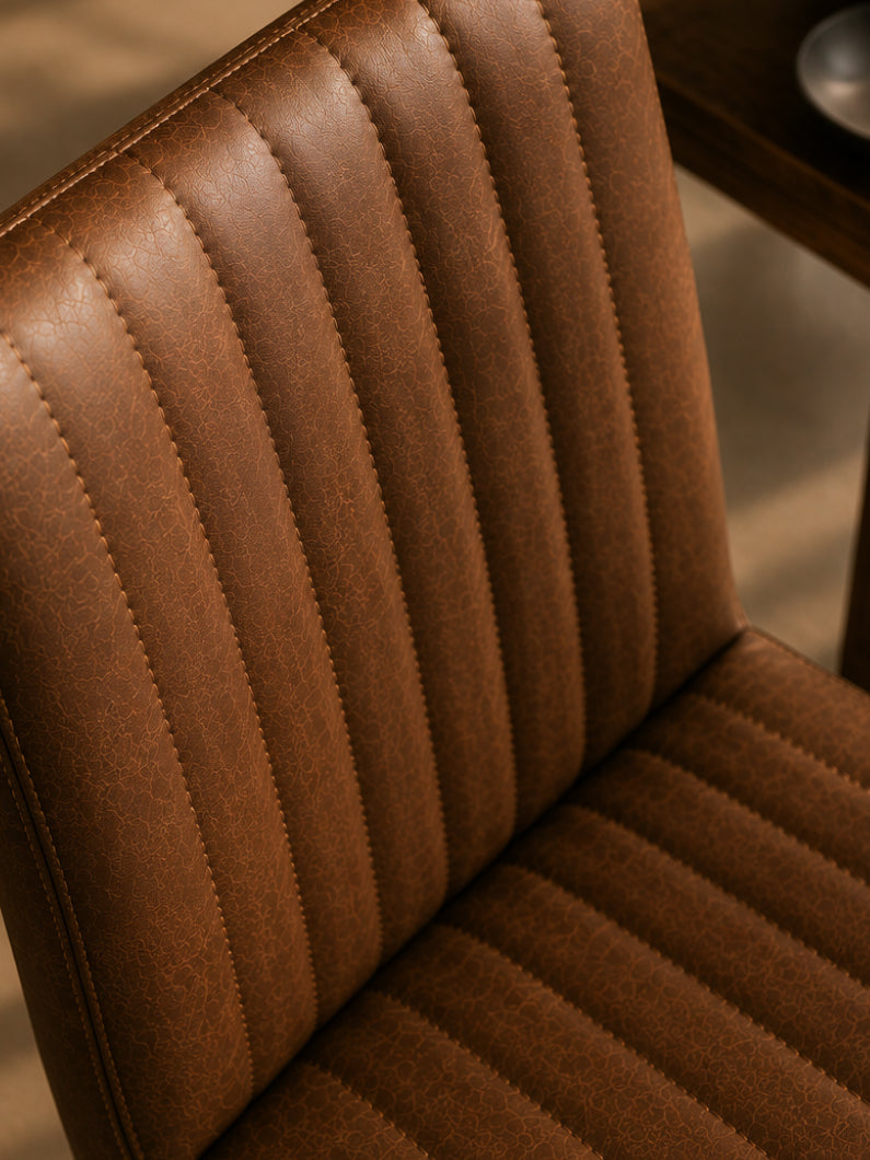 Detailaufnahme vom Stuhl Bega aus schräg oberer Perspektive mit vertikaler Steppung und braunem Bezug in Vintage-Optik