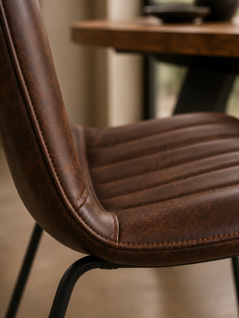 Detailaufnahme vom Stuhl Diego mit gepolsterter Sitzschale, markanter Steppung und braunem Bezug in Vintage-Optik