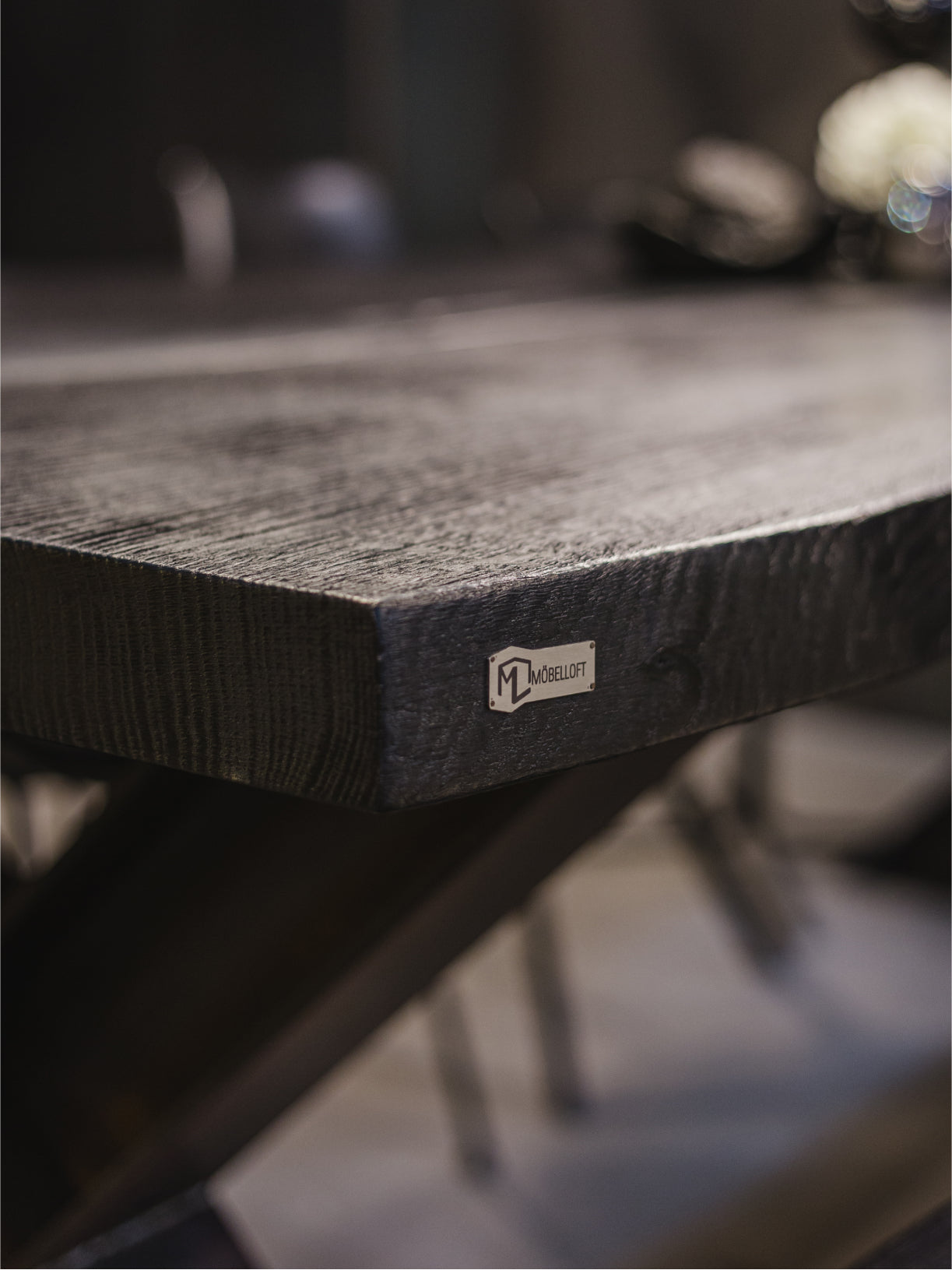Möbelloft Tisch aus schwarzer Eiche mit Stahlgestell – Plattenkante mit Möbelloft Logo im Detail, schwarze Eiche Oberfläche
