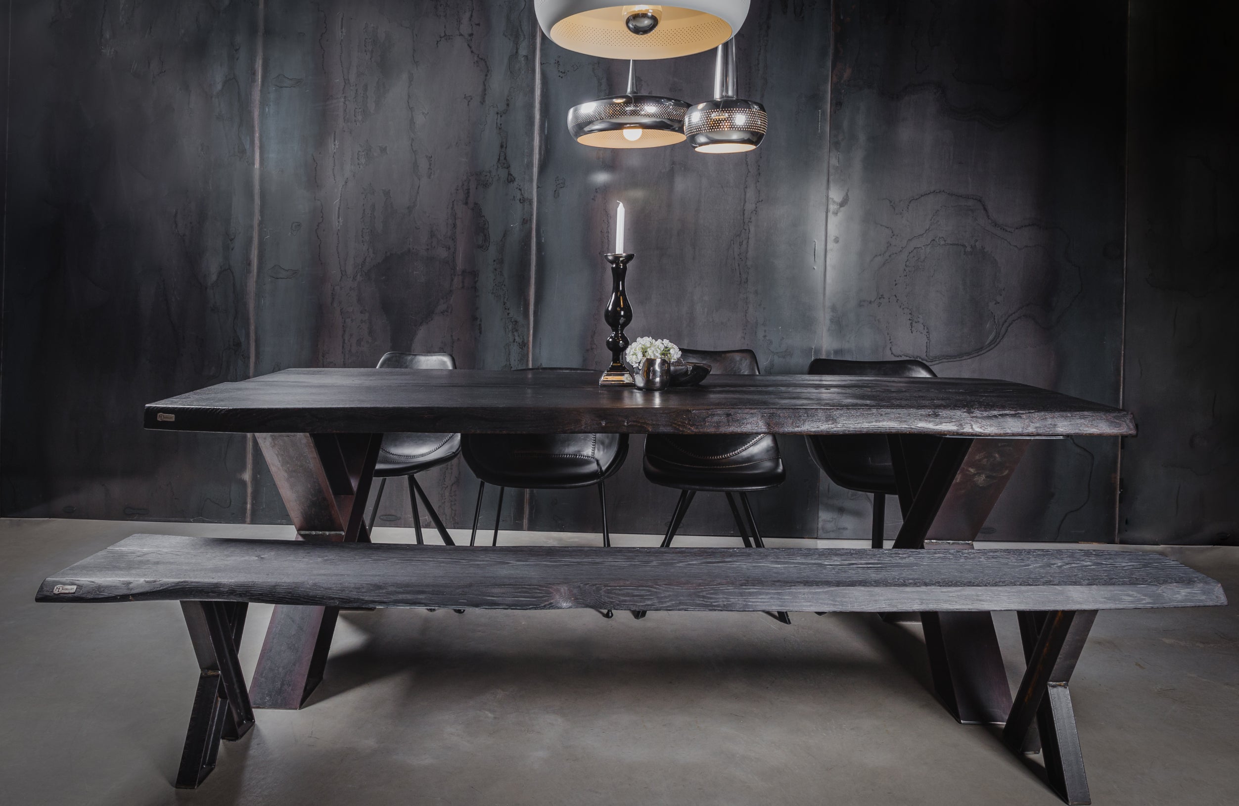 Möbelloft Tisch aus schwarzer Eiche mit Stahlgestell – Raumansicht im dunklen Loft-Stil mit Beleuchtung und Sitzgruppe