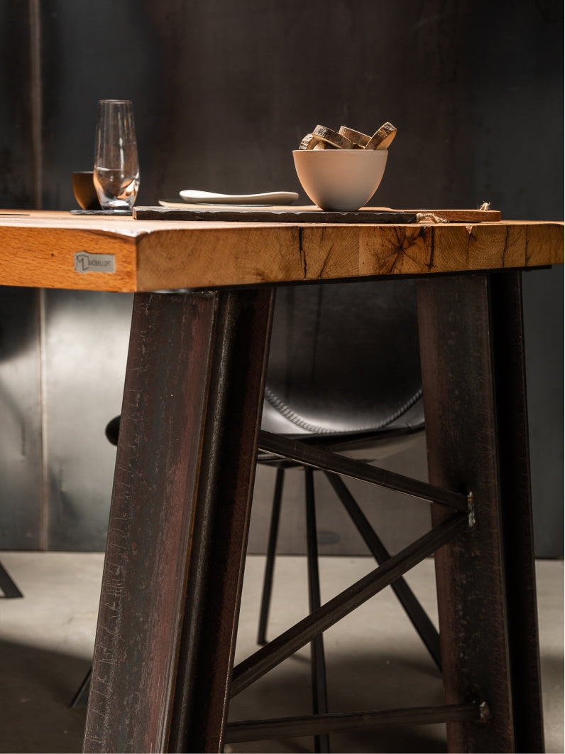 Möbelloft Tisch aus schwarzer Eiche mit Stahlgestell – Seitenansicht mit Förderturm-Gestell und passender Sitzbank im Industrial Look.
