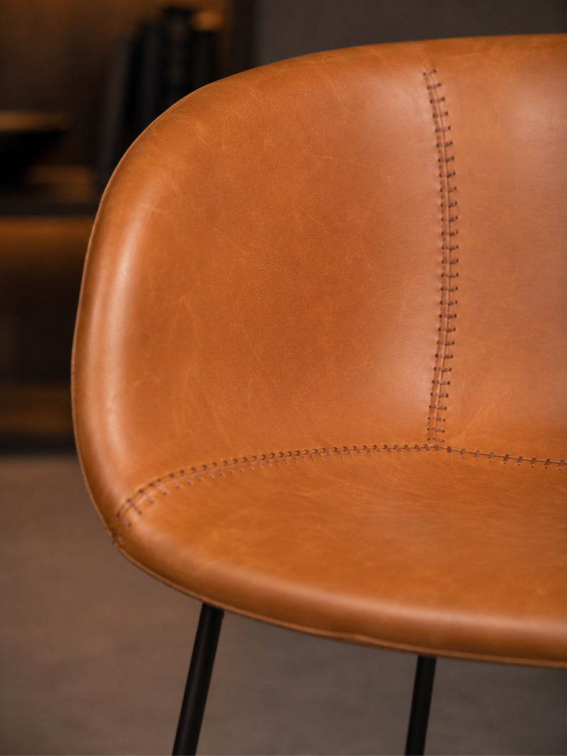 Detailaufnahme vom Design Stuhl Monkey mit cognacfarbenem Bezug, markanter Designnaht und weich gepolsterter Sitzmuschel