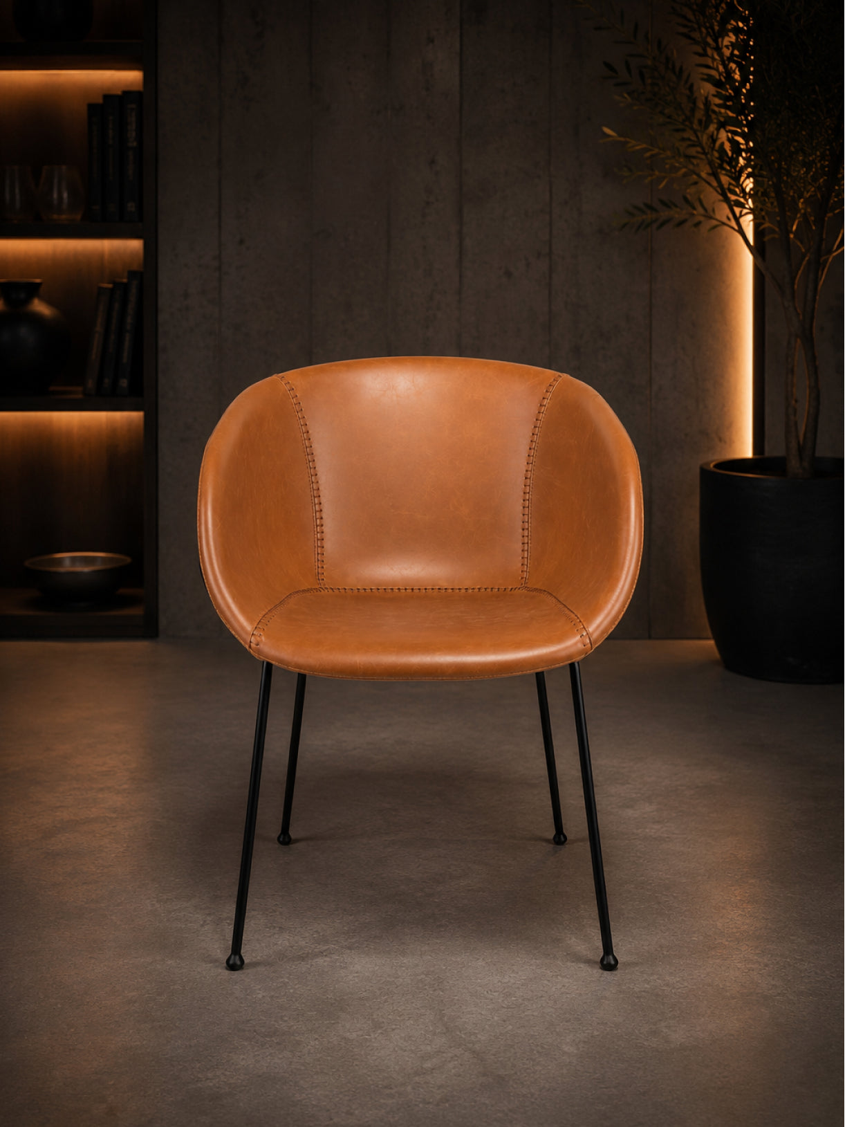 Design Stuhl Monkey in Frontalansicht mit cognacfarbenem Bezug, markanter Sitzform und schwarzem Stahlgestell