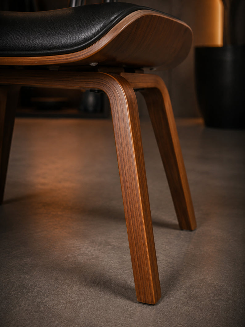 Nahaufnahme vom Design Stuhl Puma mit walnussfurniertem Holzgestell, weich gepolsterter Sitzfläche und markanter Formgebung