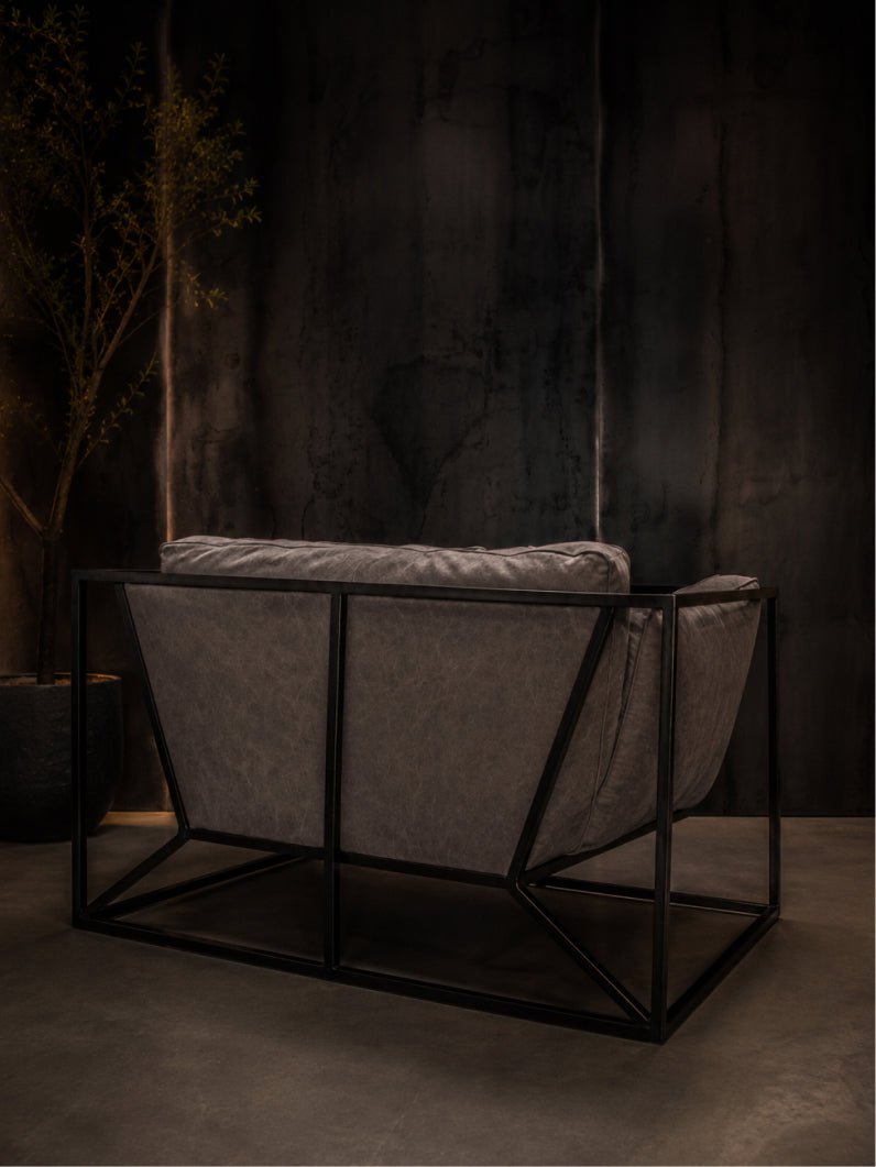 RIVER Design Sessel in schräger Perspektive mit grauem Stoff, weichen Kissen und markantem Industrial Design